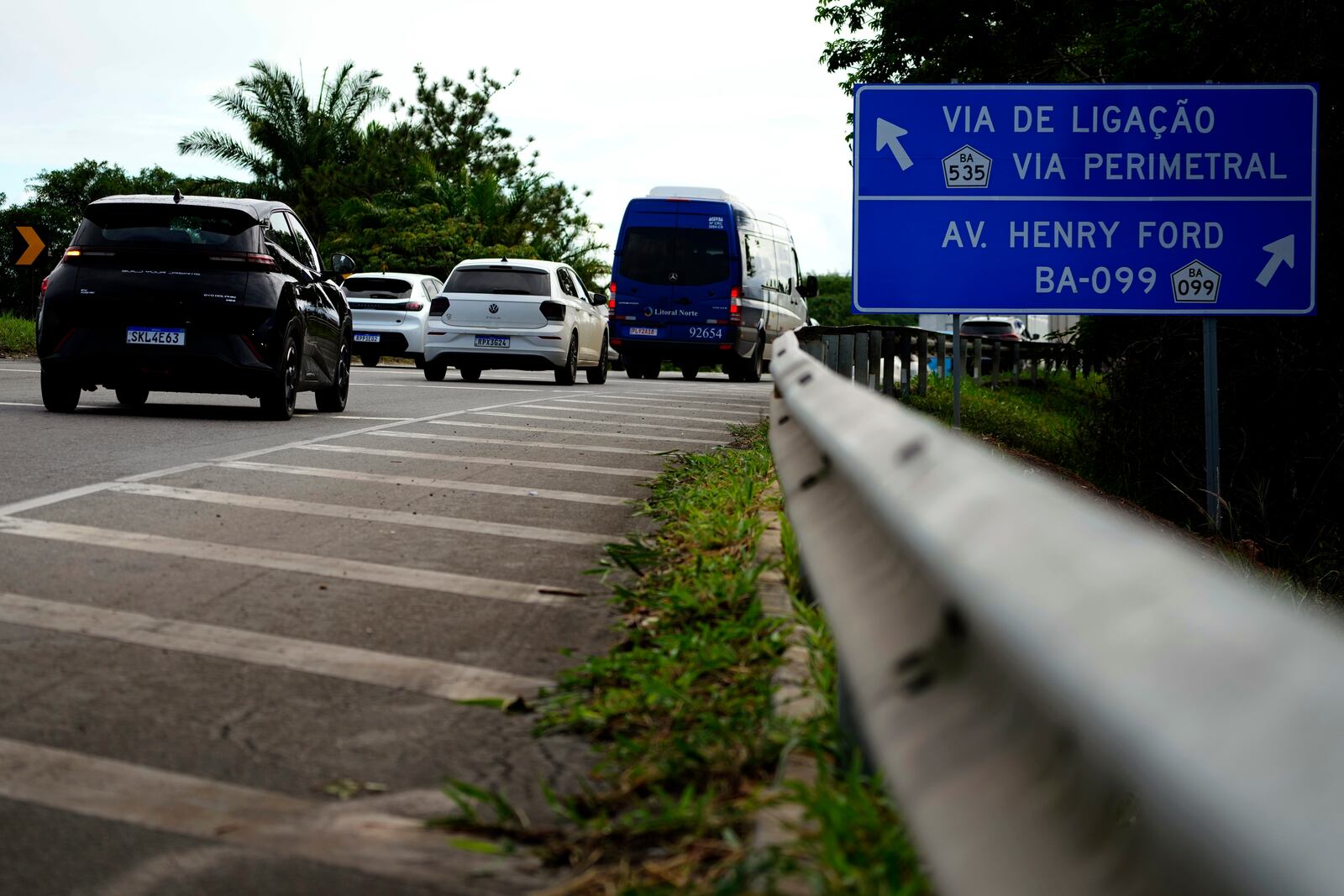 A BYD vehicle, left, passes a sign indicating Henry Ford Avenue, on the access road to the industrial complex where the BYD factory is being built, in Camacari, Bahia state, Brazil, Thursday, March 6, 2025. (AP Photo/Eraldo Peres)