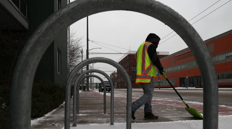 A man shovels ice off of the sidewalk in front of 711 East Monument Ave. in Dayton Feb. 3, 2022.