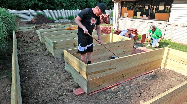 Members of the Clark County Senior Citizens Task Force work on a new handicapped accessible raised garden with paved walkways in the courtyard of the Good Shepherd Village Nursing Center. Ryan Ray, left, Alex Flora, center, and Larry Richards placing pavers around the garden Wednesday, July 12, 2023 that will allow the residents to grow flowers and vegetables. BILL LACKEY/STAFF