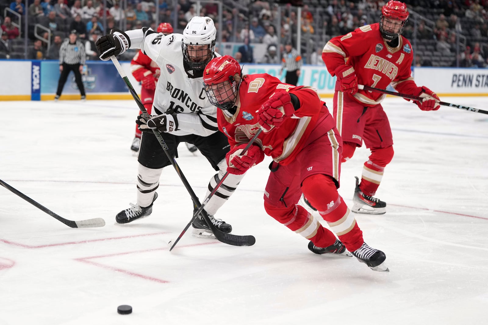 Western Michigan's Tim Washe, left, and Denver's Jack Devine (4) chase after a loose puck during the second period in a semifinal game in the NCAA Frozen Four men's college hockey tournament, Thursday, April 10, 2025, in St. Louis (AP Photo/Jeff Roberson)