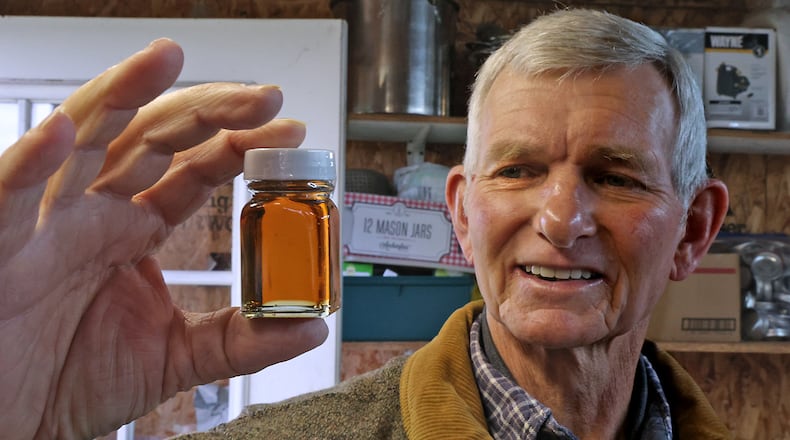 Ben Hamilton talks about how the relationship between the color of maple syrup and the taste in his backyard sugar shack Thursday. BILL LACKEY/STAFF
