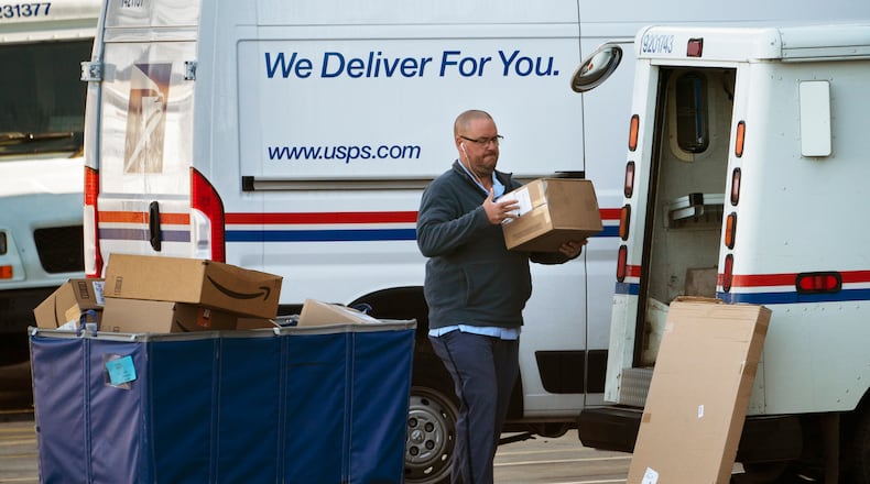 A postal carrier loads boxes into his delivery vehicle, Monday, Nov. 8, 2021, in Portland, Maine. AP FILE
