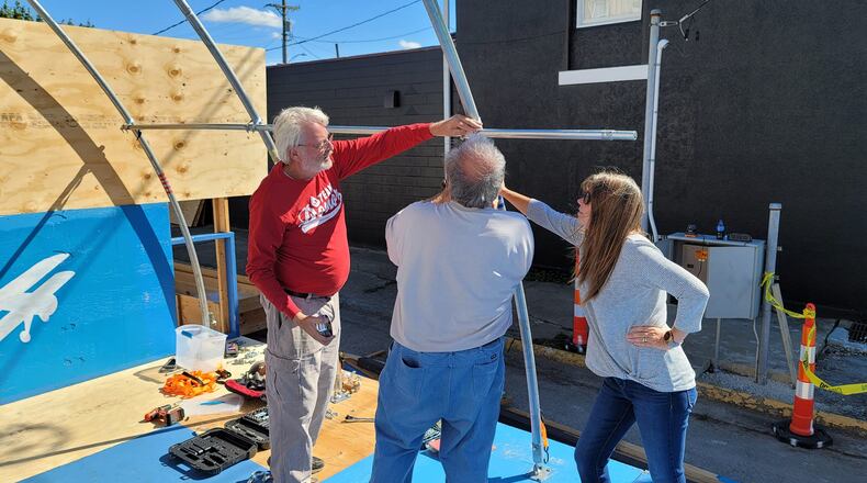 Dale Grimm and April Lowry confer with Marshall Gorby as they work to put up the Brat and Beer Hanger at Heritage of Flight. Photo by Mike Lowry.