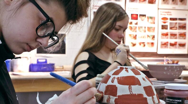 Marie Foster, left, and Brenlynn Thomas, students at the Springfield School of Innovation, paint glaze on their bowls for the Bowls For Life fund raiser at the Springfield Soup Kitchen. BILL LACKEY/STAFF