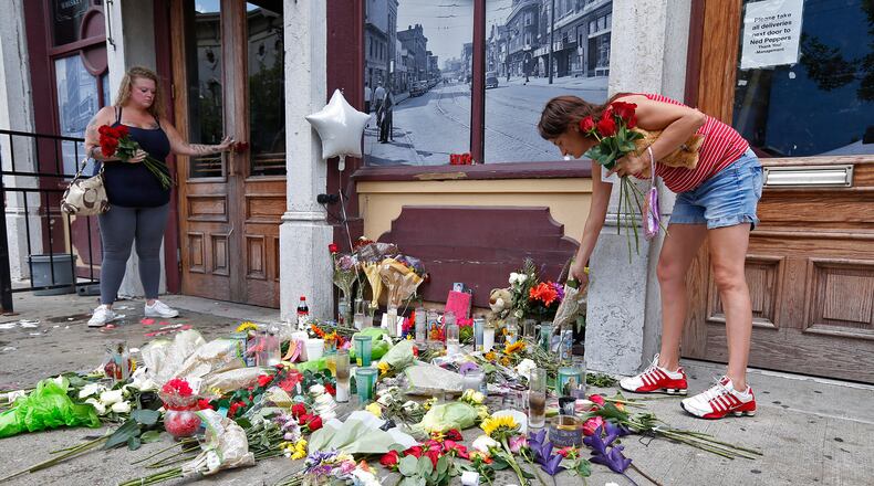 Natalie Driscoll, left, and Amber Lannon place flowers for shooting victim Derrick Fudge along East Fifth Street on Monday. TY GREENLEES / STAFF