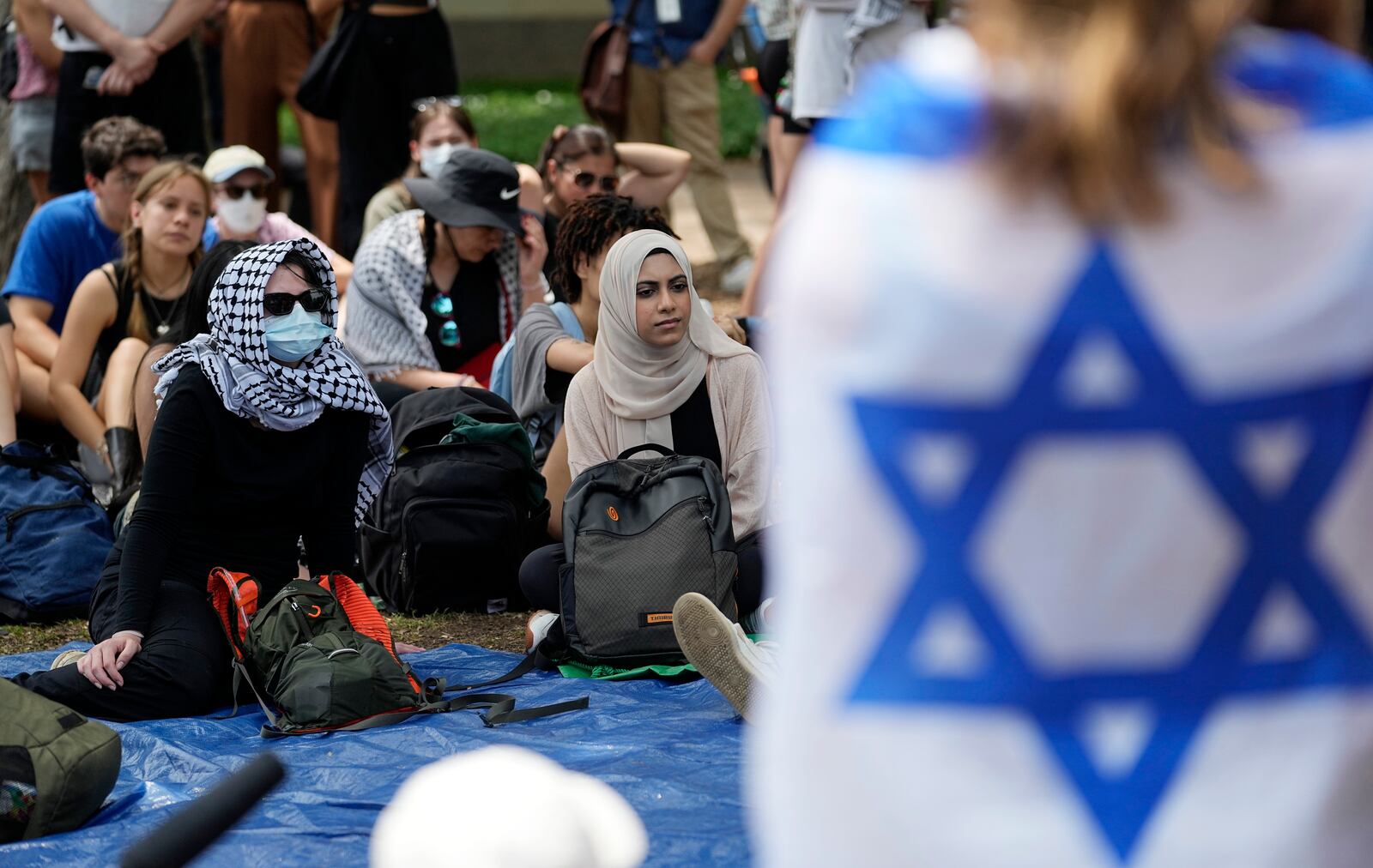 FILE - A student wrapped in an Israeli flag listens to Pro-Palestinian protesters gathered on campus at the University of Texas at Austin, on April 30, 2024, in Austin, Texas. (AP Photo/Eric Gay, File)