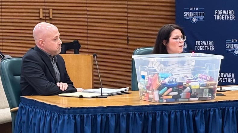 Leah Behler and Chris Cook of the Clark County Combined Health District display a bin of e-cigarettes that were confiscated from a local high school. Cook and Behler discussed the need to stiffen Springfield Tobacco Retail Licensing Program during the city commission meeting Tuesday, March 11, 2025. JESSICA OROZCO/STAFF
