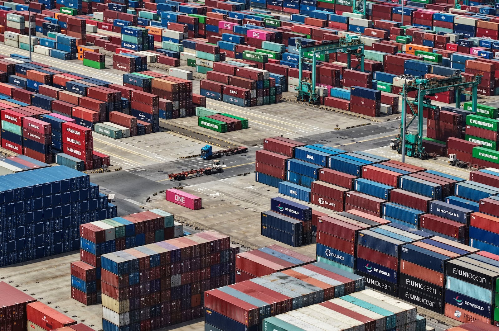 Trucks move past containers piled up at a container terminal in Shanghai, China on Friday, May 9, 2025. (Chinatopix via AP)