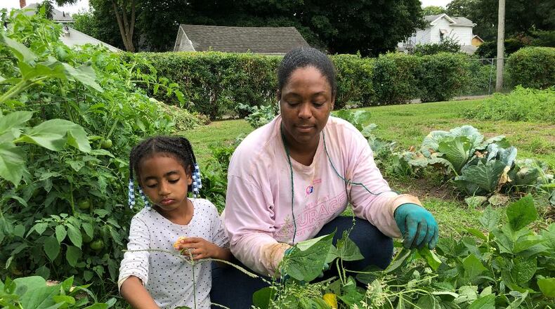 Adriel Jones and daughter Cai tend to her plot at Jefferson Street Oasis Community Garden in preparation for celebrating the garden's 10th anniversary with the Grilling in the Garden and Garden Tour event on Saturday. The community is invited to attend the admission-free event. BRETT TURNER / CONTRIBUTED