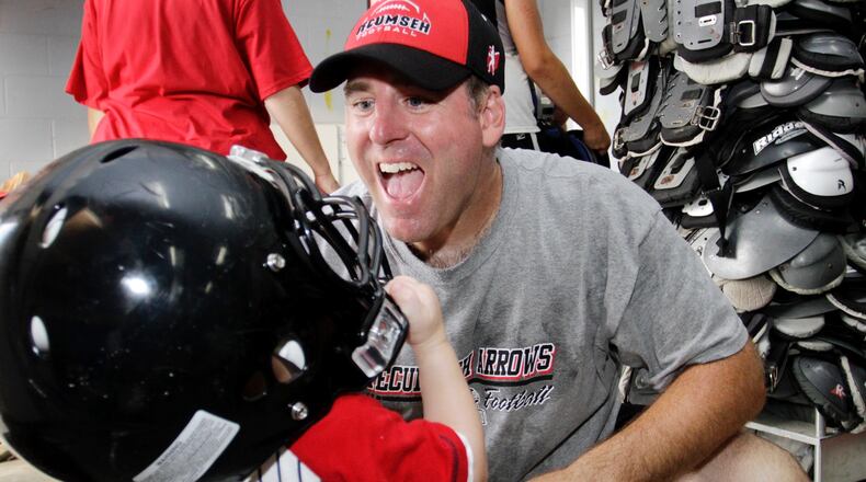 Kent Massie helps his son Dalton try on a helmet during the annual Moms Camp presented by the Tecumseh High School football team on Monday, July 19, 2010. Staff Photo by Barbara J. Perenic