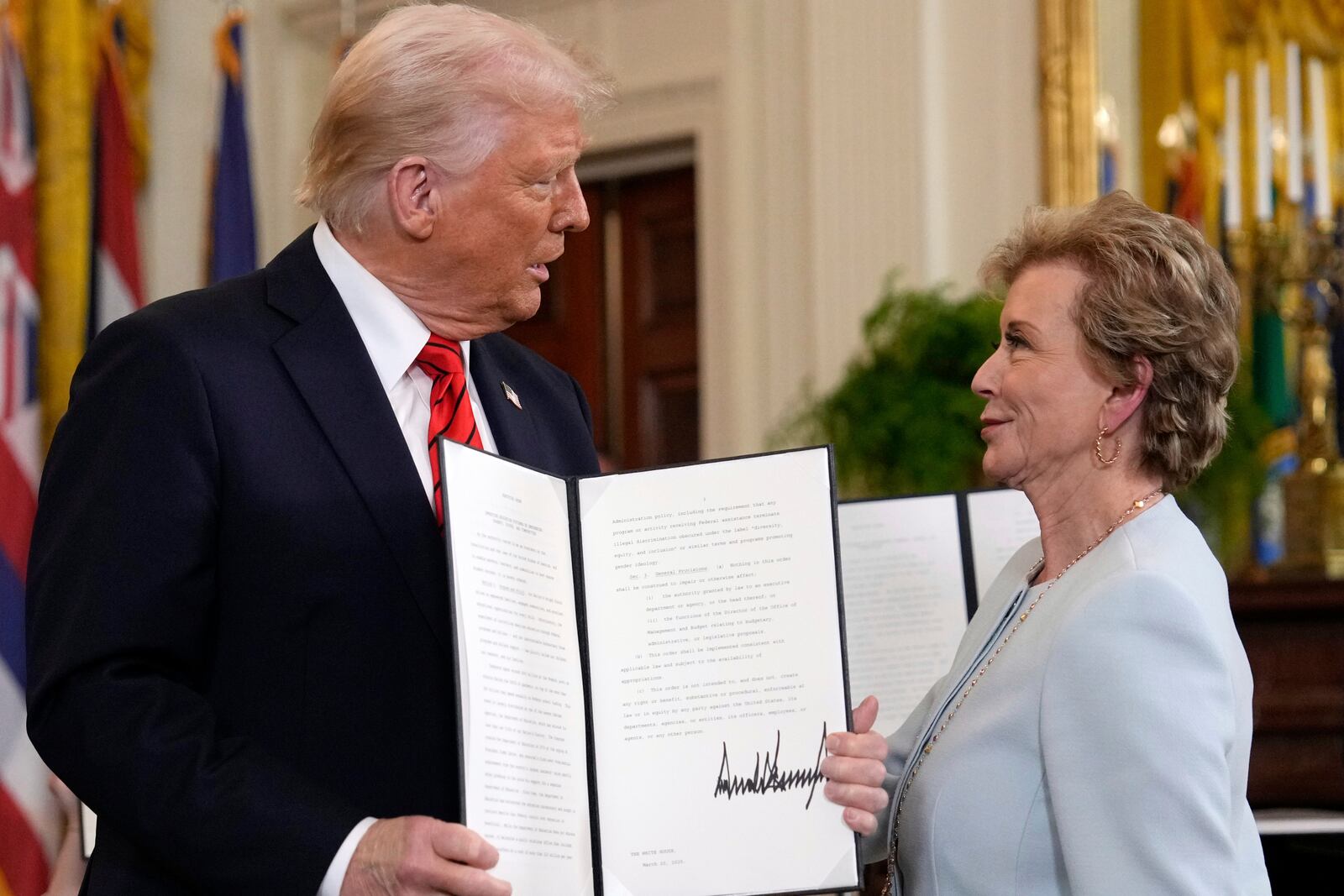 FILE - President Donald Trump holds up a signed executive order alongside Secretary of Education Linda McMahon in the East Room of the White House in Washington, March 20, 2025. (AP Photo/Ben Curtis, File)