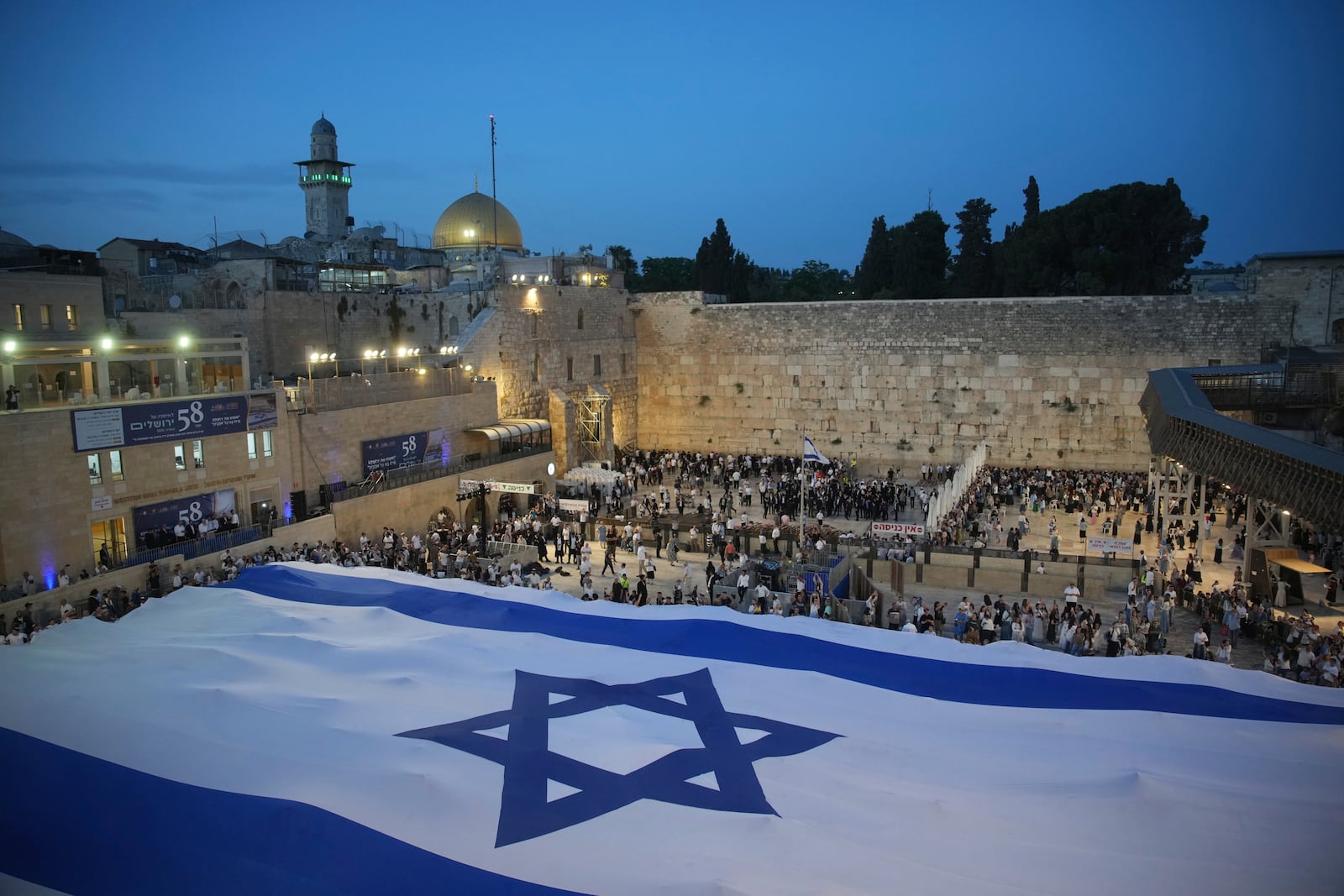 Members of Jewish youth movements unfurl a giant Israeli flag on the eve of Jerusalem Day an Israeli holiday celebrating the capture of the Old City during the 1967 Mideast war, next to the Western Wall in the Old City of Jerusalem, Sunday, May 25, 2025. (AP Photo/Ohad Zwigenberg)