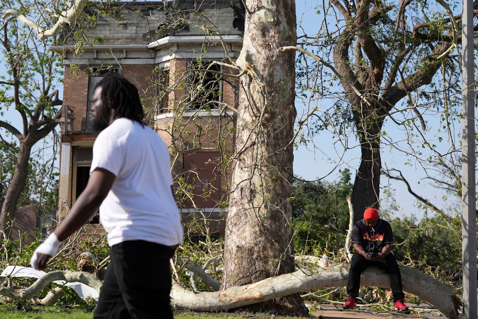 Steven Lampink sits on a downed tree after a severe storm moved through St. Louis, Missouri, Friday, May 16, 2025. (AP Photo/Jeff Roberson)
