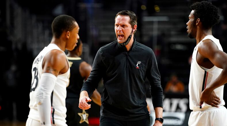 Cincinnati head coach John Brannen, center, instructs the team during a timeout in the first half of an NCAA college basketball game against Vanderbilt, Thursday, March 4, 2021, in Cincinnati. Kareem Elgazzar/The Cincinnati Enquirer via AP)