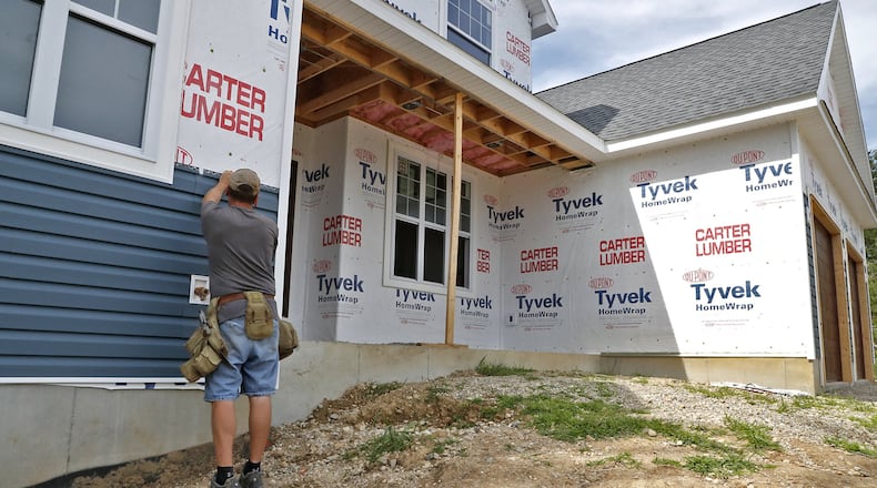 A construction worker attaches vinyl siding to the outside of a house under construction in the Northridge area in 2017. Bill Lackey/Staff