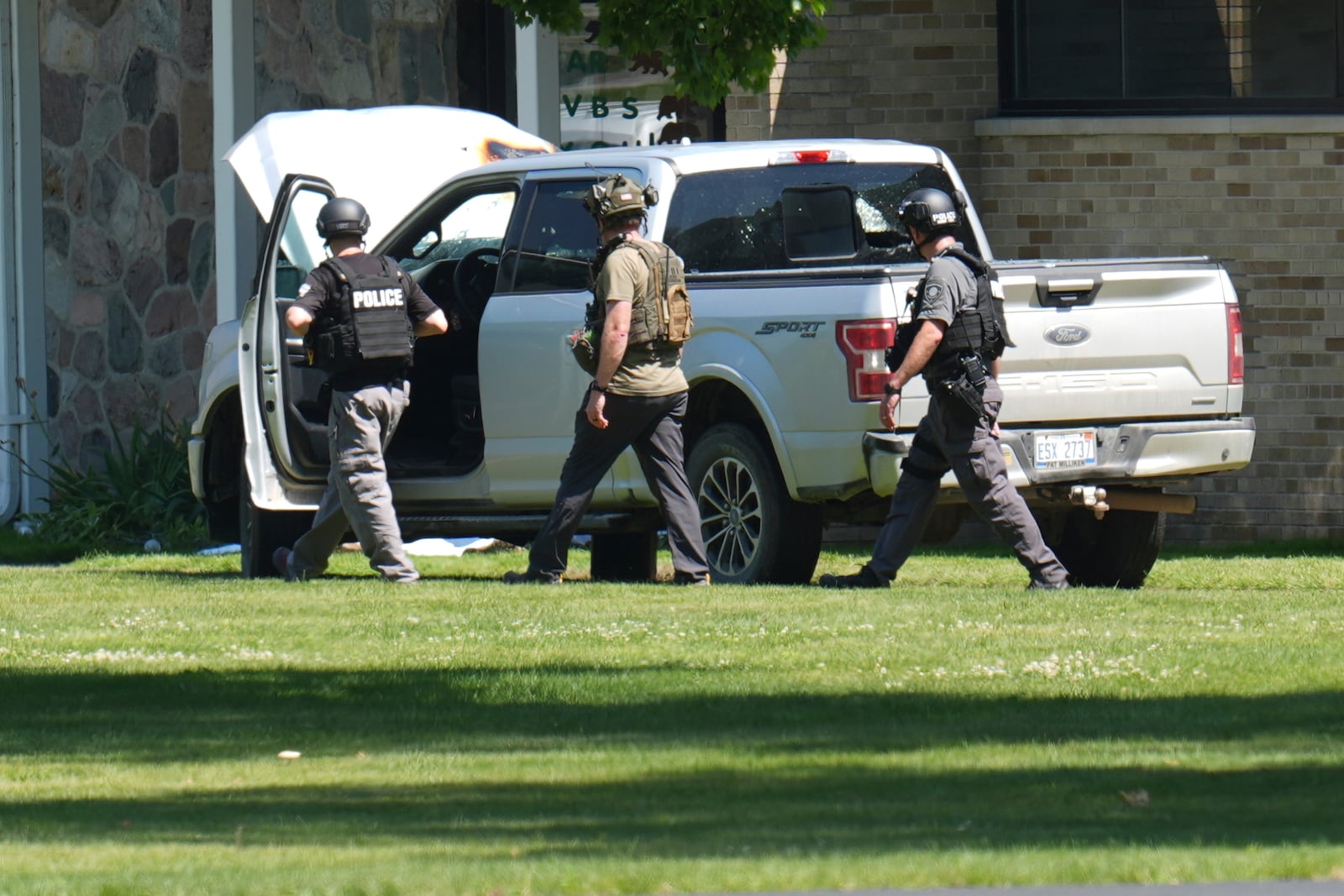 Police walk by an idle vehicle near CrossPointe Community Church in Wayne, Mich., Sunday, June 23, 2025. (AP Photo/Paul Sancya)