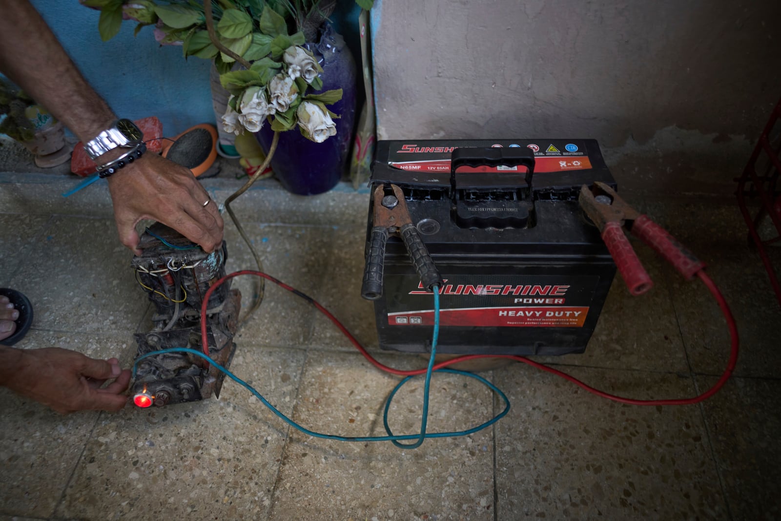 Angel Rodriguez uses a transformer from an old television to charge a battery in preparation for blackouts at his home in the Bahia neighborhood of Havana, Cuba, Monday, May 26, 2025. (AP Photo/Ramon Espinosa)