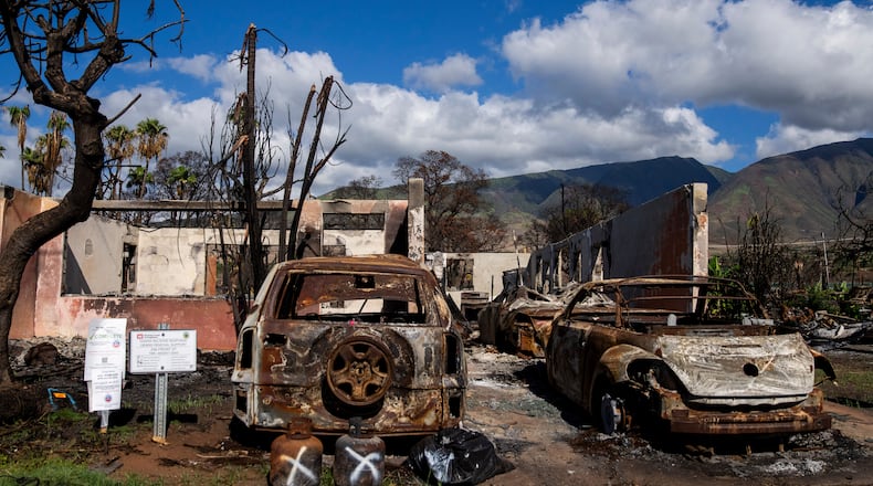 FILE - Burned cars and propane tanks with markings on them sit outside a house destroyed by wildfire, Friday, Dec. 8, 2023, in Lahaina, Hawaii. (AP Photo/Lindsey Wasson, File)