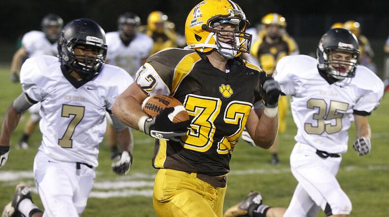 Kenton Ridge’s Christain Smith outruns Ben Logan’s Anthoni Roberts, left, and Nick Brown to the end zone as he carries the ball during Friday’s game. Unfortunatley, Smith’s run was called back due to a block in the back penalty. Bill Lackey/Staff