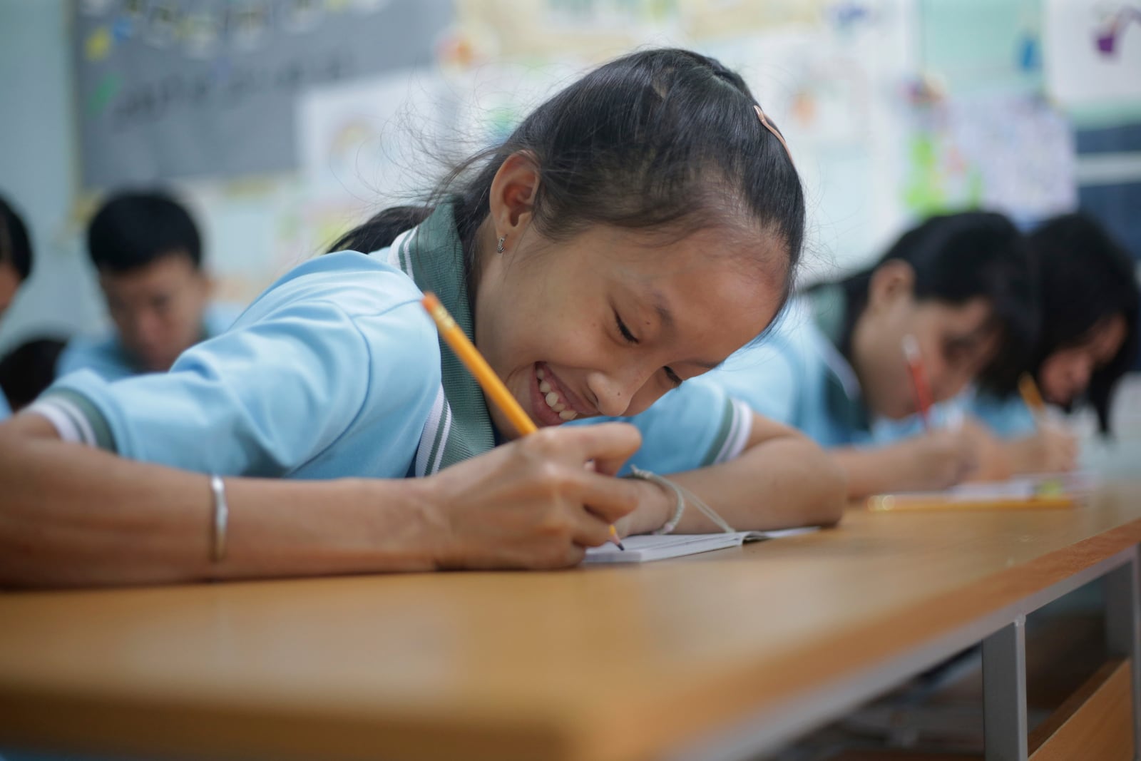 Nguyen Khanh Vy, 19, smiles while writing in her book at a school for victims of Agent Orange in Da Nang, Vietnam, March 7, 2025. (AP Photo/Aniruddha Ghosal)