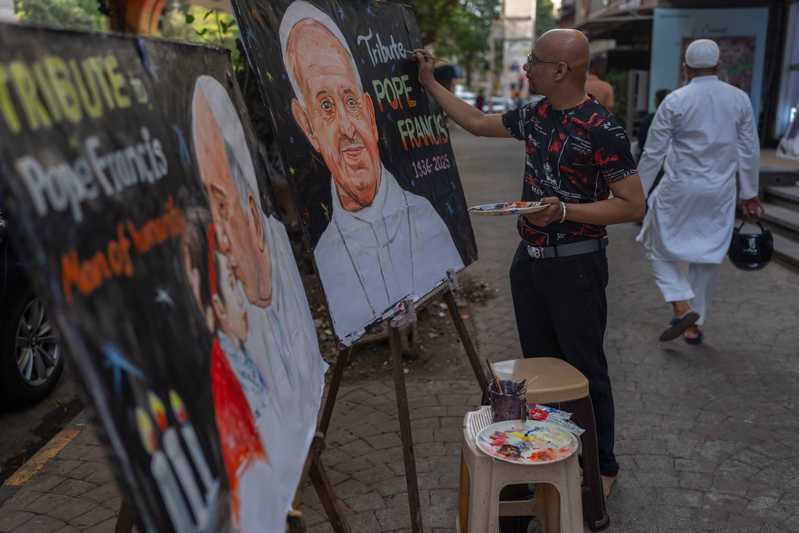 An Indian artist Sagar Kambli makes a painting of Pope Francis as a mark of tribute on a sidewalk in Mumbai, India, Monday, April 21, 2025. (AP Photo/Rafiq Maqbool)
