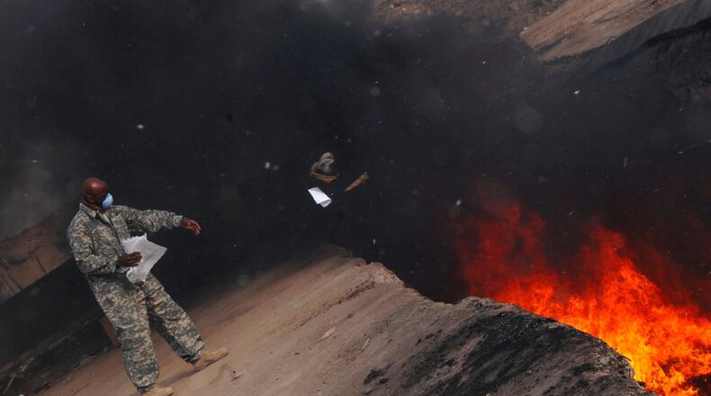 U.S. Air Force Master Sgt. Darryl Sterling tosses unserviceable uniform items into a burn pit at Balad Air Base, Iraq, on March 10, 2008. Hundreds of veterans and their families have spent eigh years in federal court trying to prove that burn pits such as this one made U.S. troops sick. (Senior Airman Julianne Showalter/US Air Force/TNS)