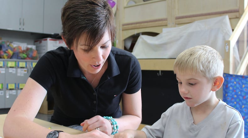 Springfield City School District employee Carrie Foley (left) helped Adrien Gillman a few years ago in Amy Day’s preschool class at the Clark Early Learning Center. STAFF/FILE