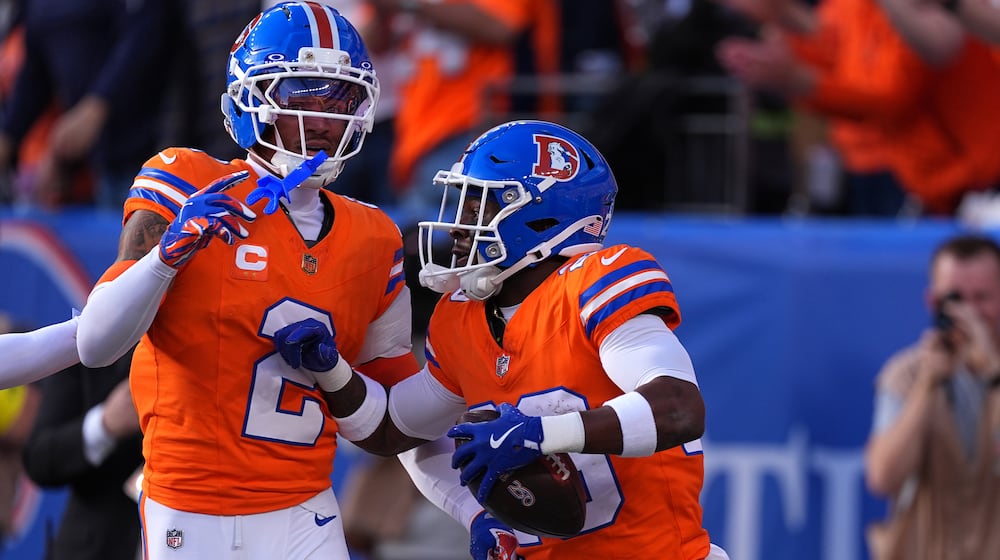 Denver Broncos cornerback Ja'quan McMillian, right, celebrates with cornerback Pat Surtain II (2) after scoring a touchdown on an interception against the Los Angeles Chargers in the first half of an NFL football game Sunday, Jan. 4, 2026, in Denver. (AP Photo/David Zalubowski)