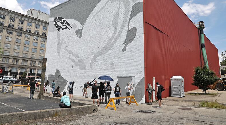 Work has started on a mural on the back wall of The State theater in downtown Springfield Wednesday, June 1, 2022. A television production crew was filming people working on the mural Wednesday. BILL LACKEY/STAFF