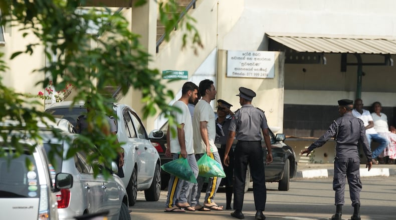 Two Iranian sailors, carrying green bags, who were rescued from IRIS Dena warship by Sri Lanka's navy are escorted to a Judicial Medical Officer from the National Hospital, in Galle, Sri Lanka, Thursday, March 5, 2026. (AP Photo/Eranga Jayawardena)