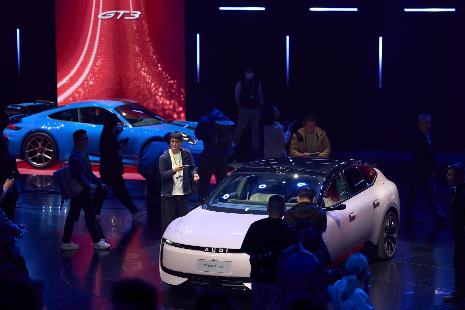 Attendees look at the latest cars from Volkswagen Group during the media night ahead of the Auto Show in Shanghai, Tuesday, April 22, 2025. (AP Photo/Ng Han Guan)