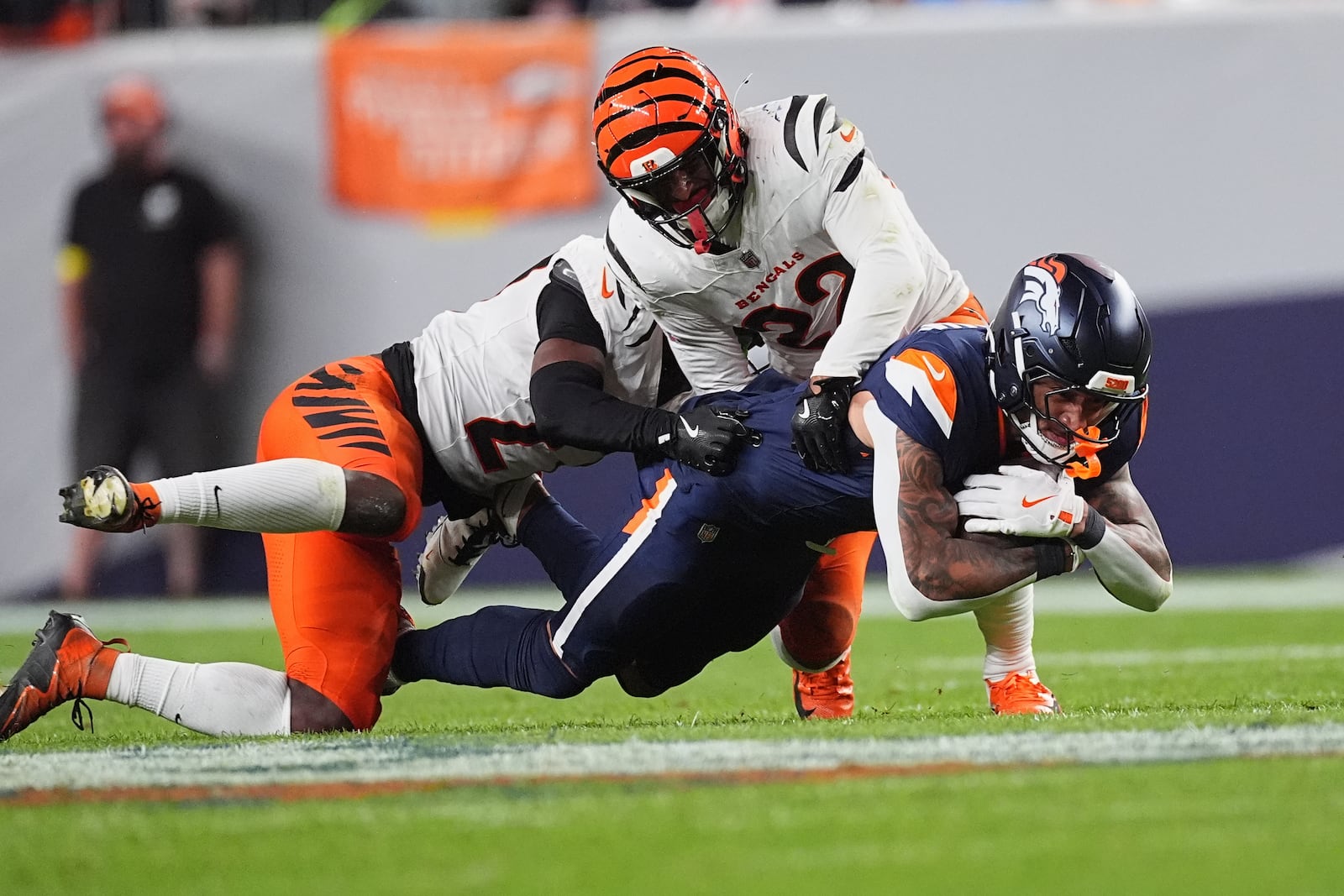 Cincinnati Bengals safety Jordan Battle, left, and Cincinnati Bengals safety Geno Stone (22) tackle Denver Broncos tight end Evan Engram (1) during the second half of an NFL football game Monday, Sept. 29, 2025, in Denver. (AP Photo/David Zalubowski)