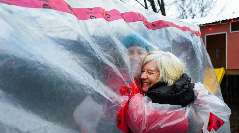 Carolyn Ellis, left, creator of the hug glove hugs her mother Susan Watts, 74, in her backyard on Christmas Eve during the COVID-19 pandemic in Guelph, Ont., Thursday, Dec. 24, 2020. Watts is a retired nurse who lives in an apartment near by and gets to come over outside and hug her daughter's family.  (Nathan Denette/The Canadian Press via AP)