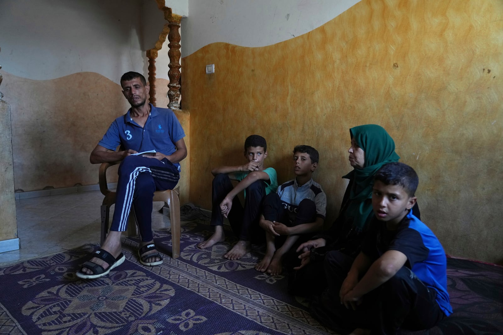 Hatem Al-Nouri, the father of two children who were killed, and one injured, in an Israeli strike while waiting to receive nutritional supplements at a medical clinic, sits with his family during an interview at his home in Deir al-Balah, Gaza Strip, Friday, July 11, 2025. (AP Photo/Abdel Kareem Hana)