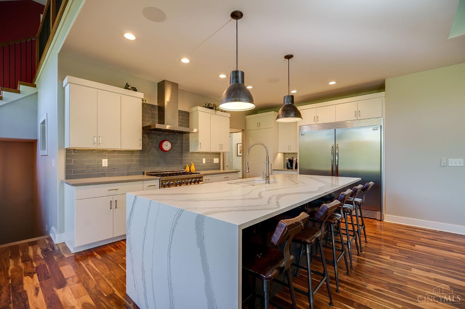 The kitchen has hardwood flooring, a custom quartz island with bar seating and stainless appliances, including a sub zero refrigerator. CONTRIBUTED