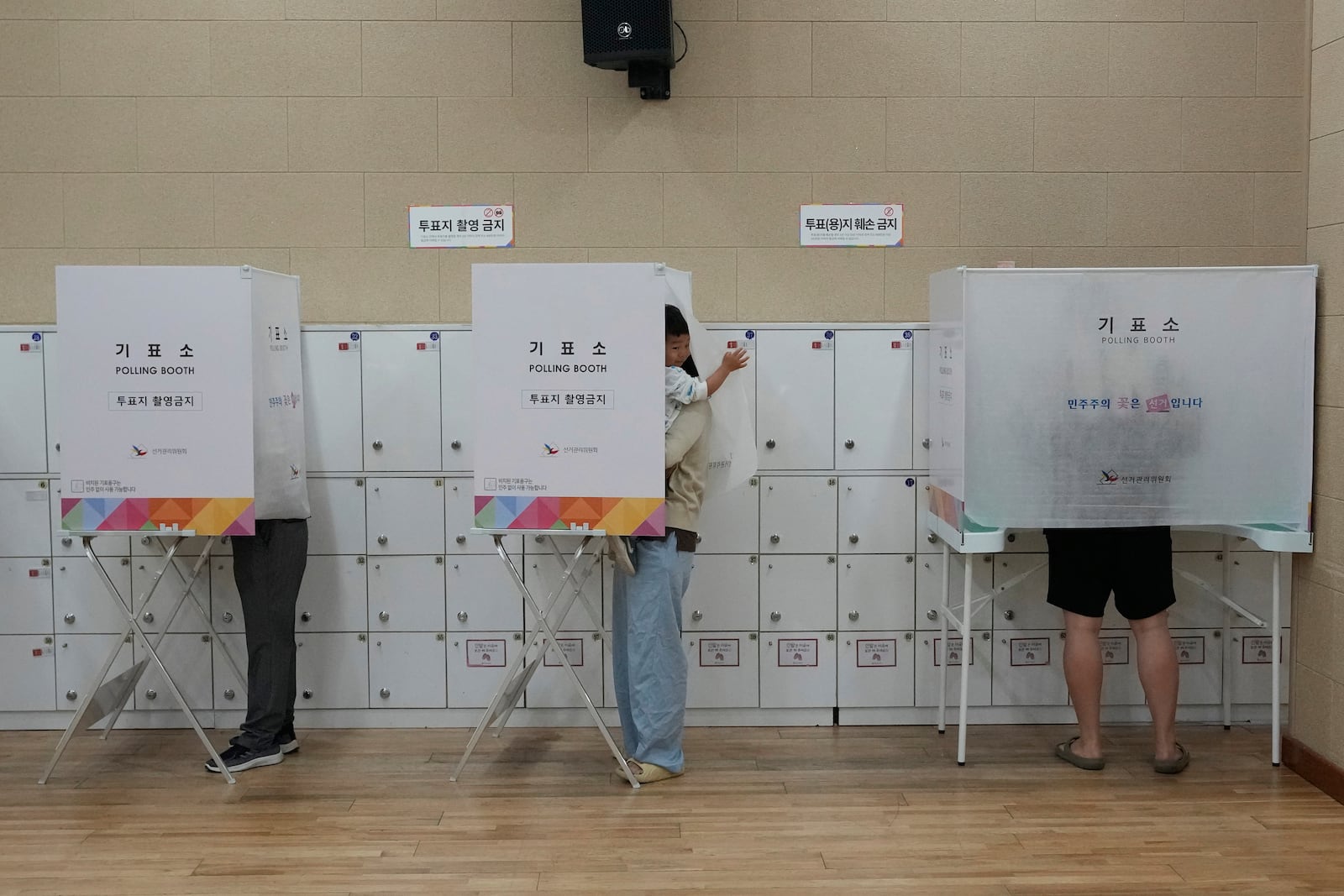 FILE - A boy waits for his mother casting her early vote for the June 3 presidential election at a polling station in Seoul, South Korea, Thursday, May 29, 2025. (AP Photo/Ahn Young-joon, File)