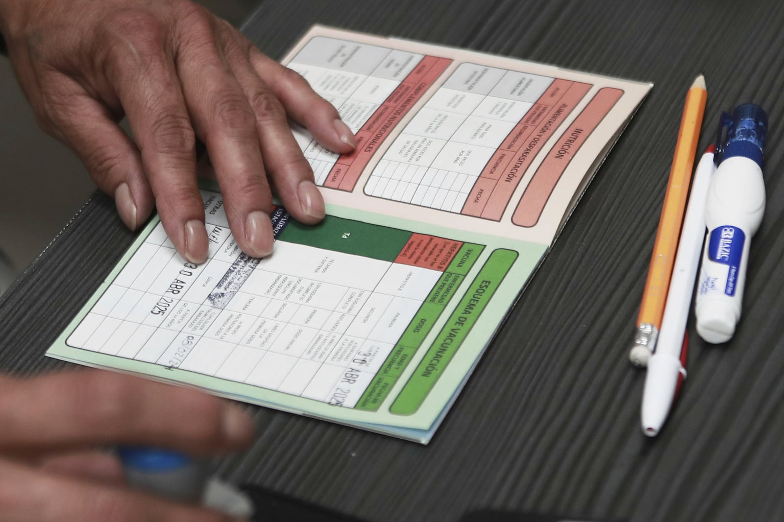 A health worker stamps a vaccination card at the health center where measles vaccinations are given in Ciudad Juarez, Chihuahua state, Mexico, Wednesday, April 30, 2025. (AP Photo/Christian Chavez)