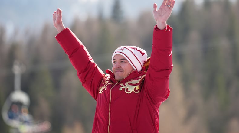 Aleksei Bugaev, of Russia, waves from the podium after winning the bronze medal in the alpine skiing men's downhill standing competition at the 2026 Winter Paralympics, in Cortina d'Ampezzo, Italy, Saturday, March 7, 2026. (AP Photo/Emilio Morenatti)