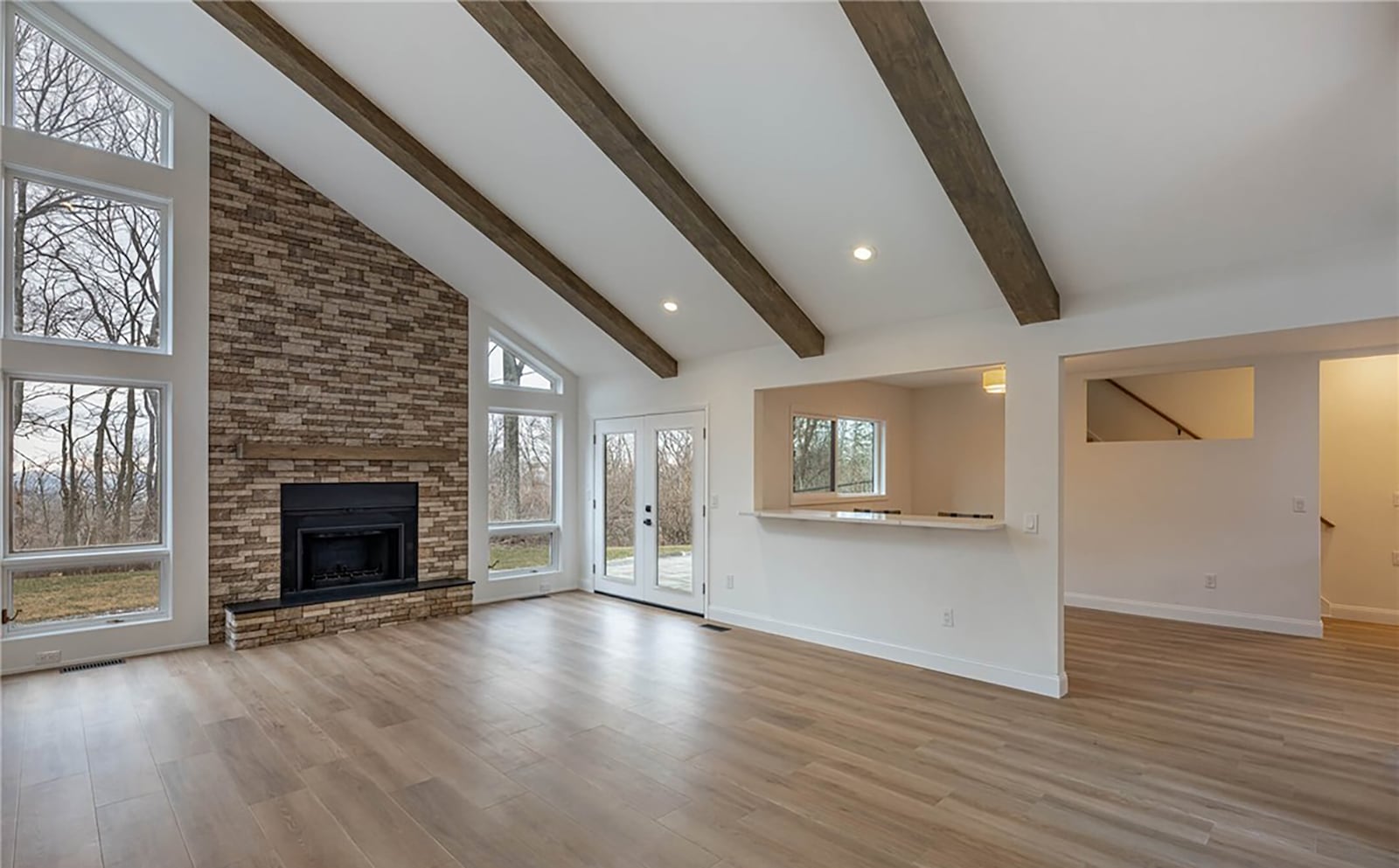 The living room at the rear of the home has a wood beamed, vaulted ceiling, recessed lighting, a stacked stone fireplace and floor to ceiling windows on either side. CONTRIBUTED