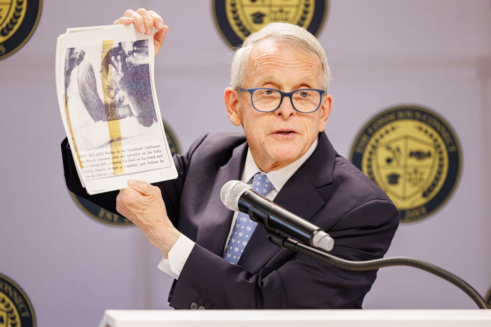 Gov. Mike DeWine holds up a picture of Brooks Lawrence from a scrapbook he collected as a child during a ceremony unveiling a historical marker for Lawrence on Friday, Nov. 14 at The Dome on South Limestone Street. Lawrence, a Springfield native, broke the color barrier on Miami University's baseball team and for a St. Louis AAA minor league team. He later was a star pitcher with the Reds, and DeWine was a fan when he was a child. BRYANT BILLING/STAFF
