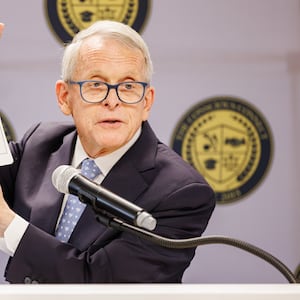 Gov. Mike DeWine holds up a picture of Brooks Lawrence from a scrapbook he collected as a child during a ceremony unveiling a historical marker for Lawrence on Friday, Nov. 14 at The Dome on South Limestone Street. Lawrence, a Springfield native, broke the color barrier on Miami University's baseball team and for a St. Louis AAA minor league team. He later was a star pitcher with the Reds, and DeWine was a fan when he was a child. BRYANT BILLING/STAFF