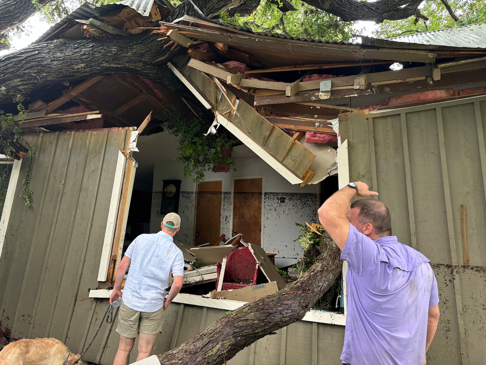 A tree sits on a damaged cabin in Hunt, Texas, at 2:33 p.m. on Friday, July 4, 2025, with lines indicating the height of floodwaters from the Guadalupe River. (Shabd Simon-Alexander via AP)