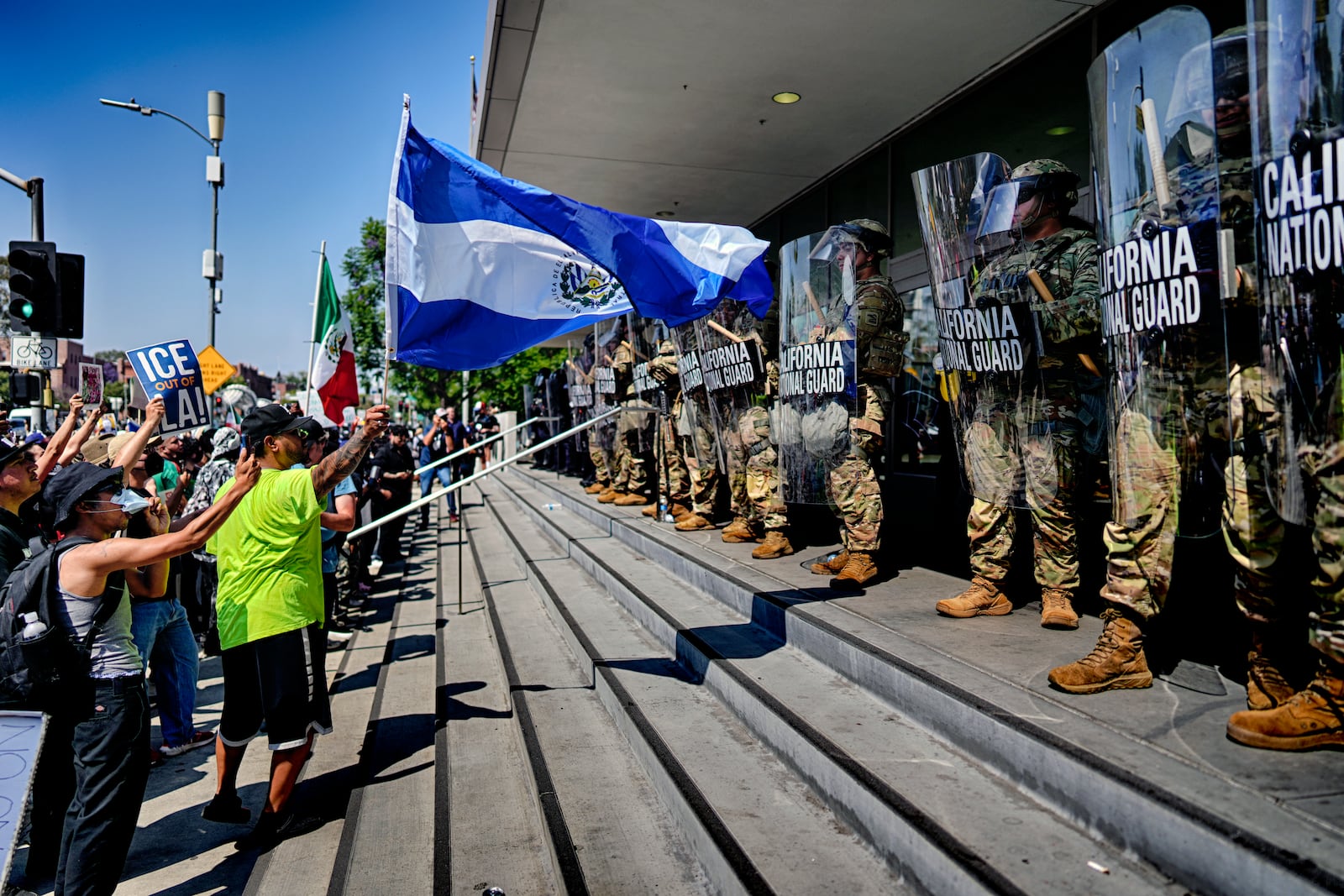 A protester waves a National Flag of El Salvador in front of a line of California National Guard in front of Federal Building on Monday, June 9, 2025, in downtown Los Angeles. (AP Photo/Eric Thayer)