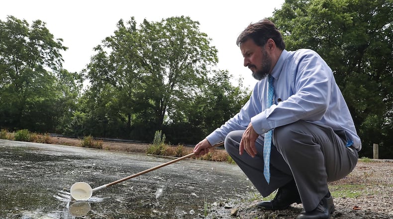 Larry Shaffer, the director of Environment Health at the Clark County Combined Health District, skims the top of the water at Old Reid Park as he looks for mosquito larvae Monday. BILL LACKEY/STAFF