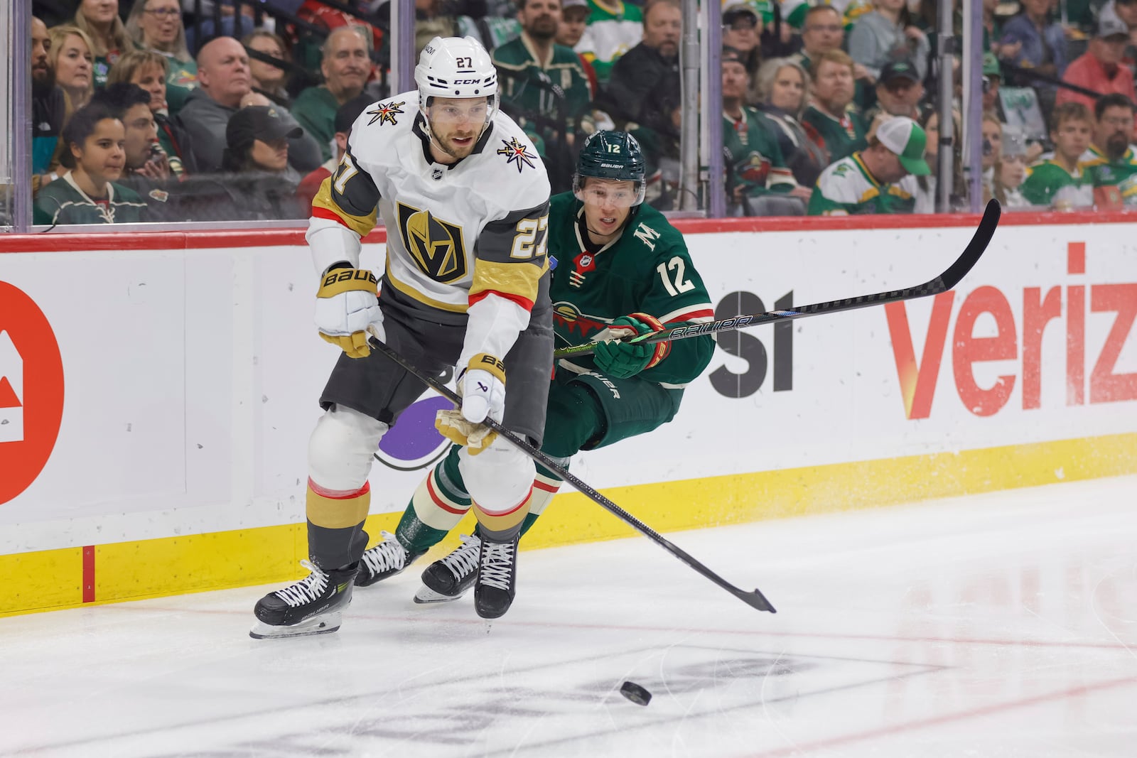Minnesota Wild left wing Matt Boldy (12) and Vegas Golden Knights defenseman Shea Theodore (27) battle for the puck during the first period of Game 6 of a first-round NHL hockey playoff series Thursday, May 1, 2025, in St. Paul, Minn. (AP Photo/Bailey Hillesheim)