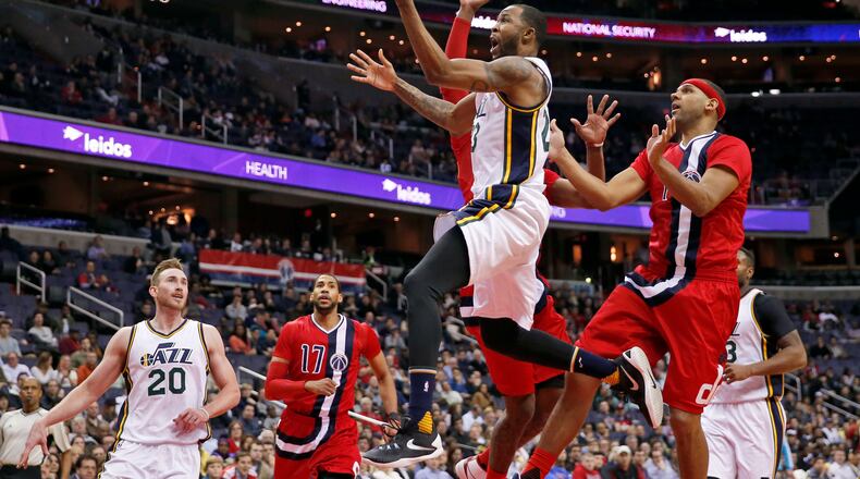 Utah Jazz forward Chris Johnson, center, drives to the basket with Washington Wizards forward Jared Dudley (1) behind him, during the second half of an NBA basketball game Thursday, Feb. 18, 2016, in Washington. The Wizards won 103-89. (AP Photo/Alex Brandon)