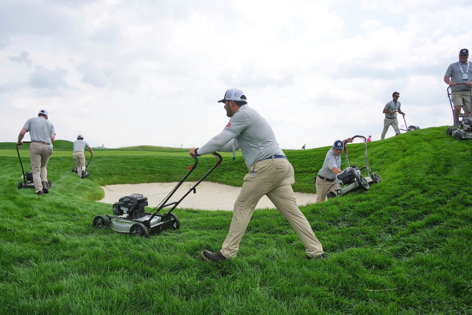 The rough surrounding a fairway bunker on the 18th hole gets trimmed during a practice round for the 2025 US Open golf championship at Oakmont Country Club in Oakmont, Pa., Monday, June 9, 2025. (AP Photo/Gene J. Puskar)