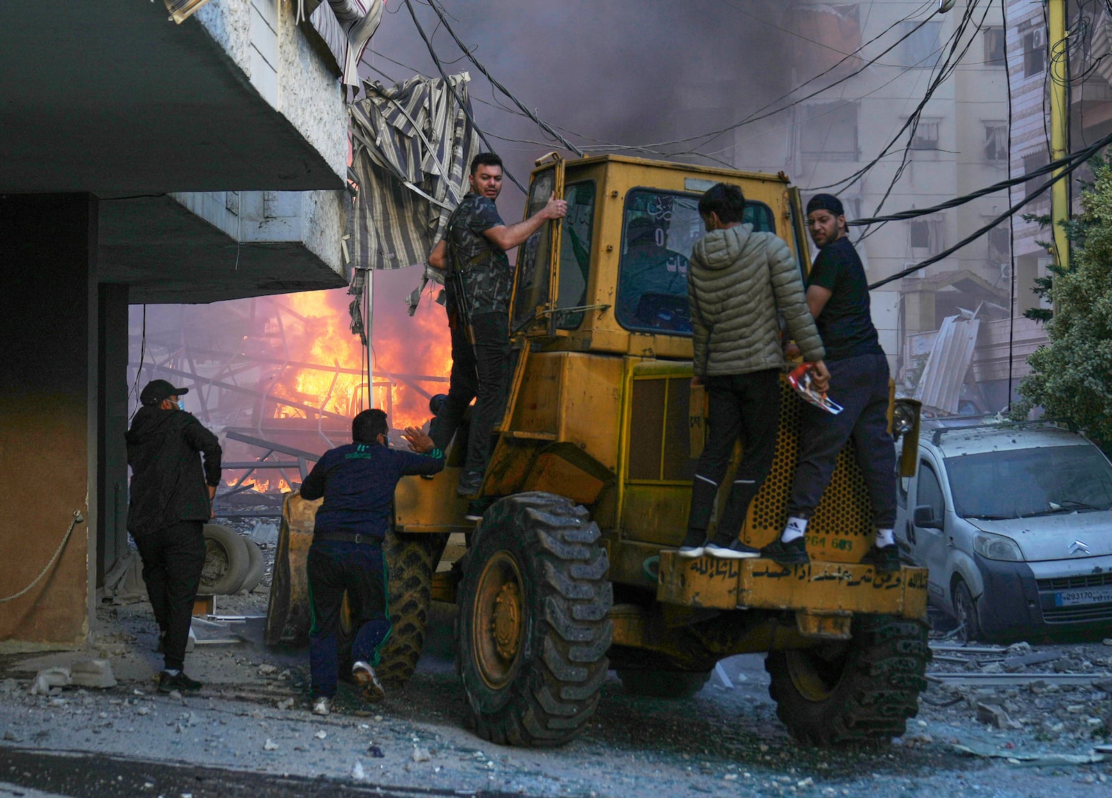 A bulldozer arrive to remove debris as flames rise from a metal tent that was hit by an Israeli airstrike on Dahiyeh in the southern suburb of Beirut, Lebanon, Sunday, April 27, 2025. (AP Photo/Hussein Malla)
