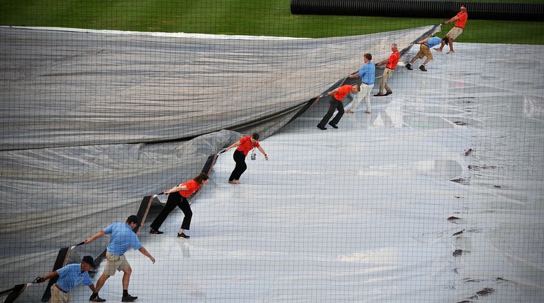 Ground crews remove the tarp from the field at Day Air Ballpark after a heavy rainfall Friday, Aug. 20, 2021, moved through downtown Dayton. MARSHALL GORBY\STAFF