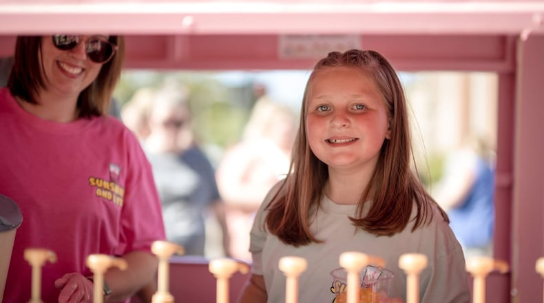 Urbana fourth grader Lydia Martinez (front right) with her mom, Abby Martinez, at the Sunshine and Lyds drink stand that is in a converted 4-H trailer. Lydia, 9, opened the lemonade stand earlier this summer, making creative drink mixes to sell at various events. CONTRIBUTED